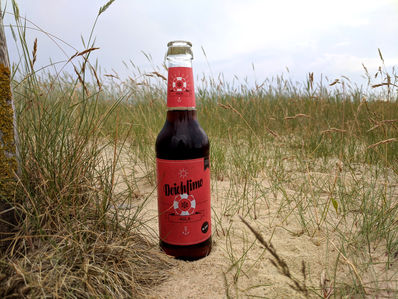 Foto einer Flasche Deichlimo Kola auf einer Düne